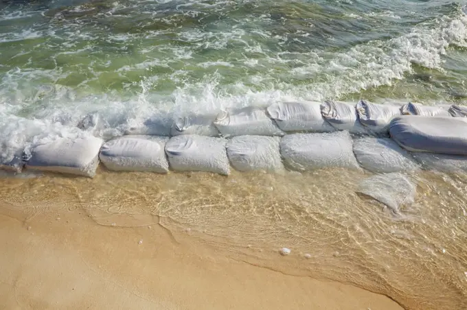 Sandbags in rows at the water's edge to prevent erosion of the beach