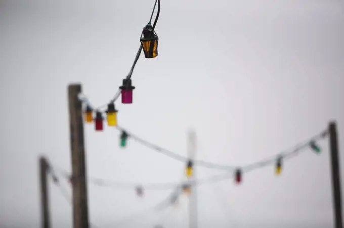 A multicoloured string of electric lights against a grey sky.