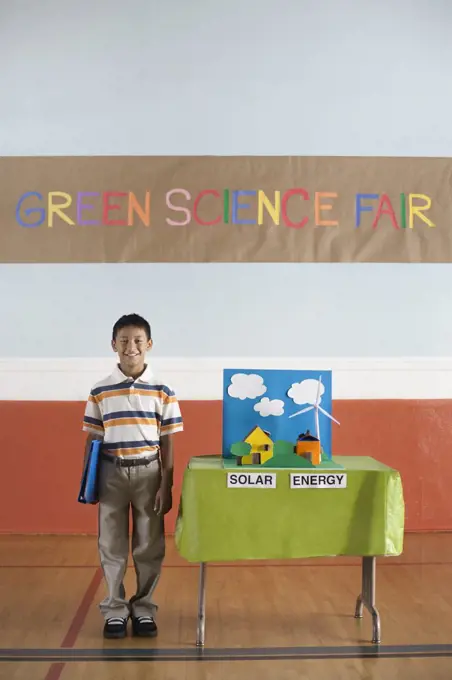 A boy standing under a Green Science Fair sign beside a Solar Power presentation.