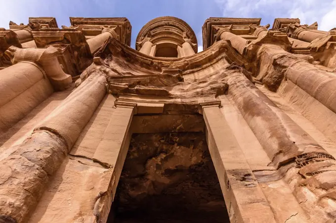 Low angle exterior view of the rock-cut architecture of El Deir or The Monastery at Petra, Jordan.
