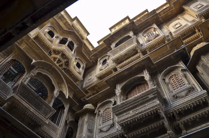 View up from the ground inside a historic fortified building in Jaisalmer. Traditional architecture, windows and balconies.