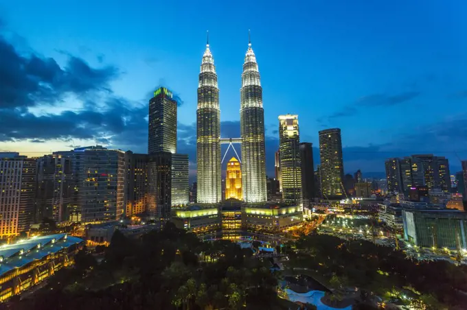 Cityscape of Kuala Lumpur in the evening, with the illuminated Petronas Towers in the distance, Malaysia.