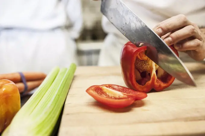 Close-up of a chef using a knife to chop vegetables.