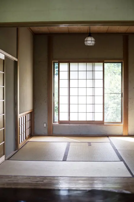 Interior of traditional Japanese house with tatami mats and opaque sliding doors.