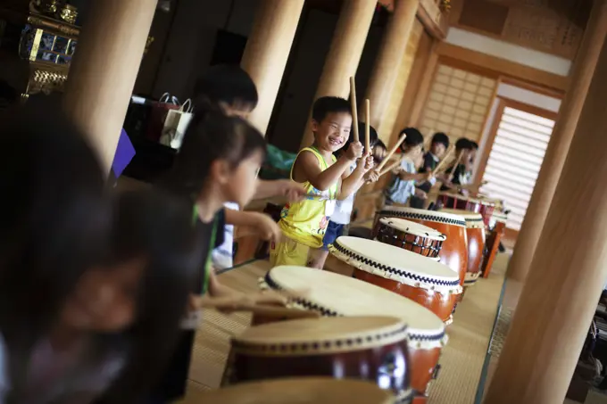 Group of children playing the drums in a temple, a traditional set of drums. 
