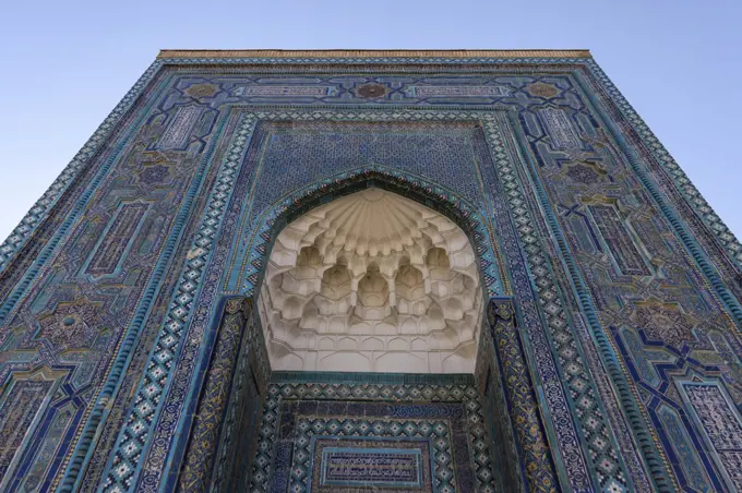Registan square in Samarkand, a huge arch covered in glazed patterned tiles, blue white and golden, and a carved dome.