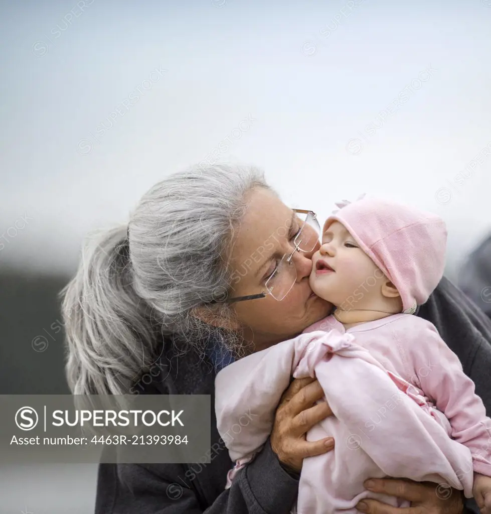 Grandmother holding her baby granddaughter on the beach.