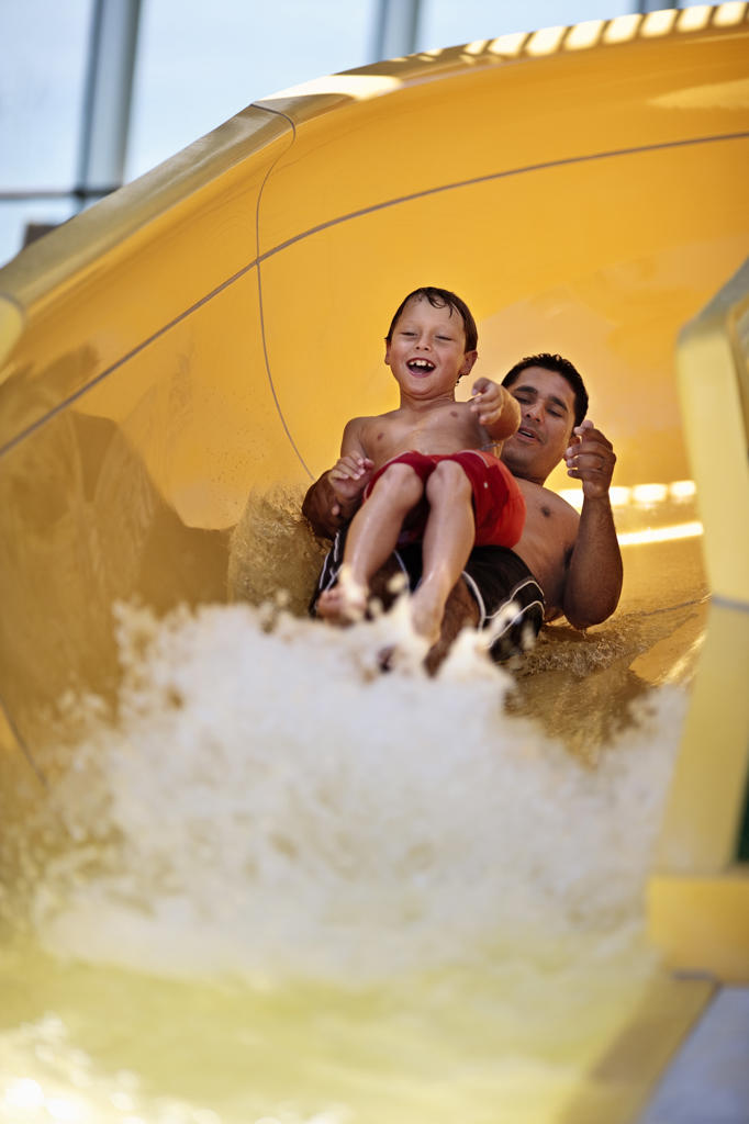 Father and son going down a waterslide together.