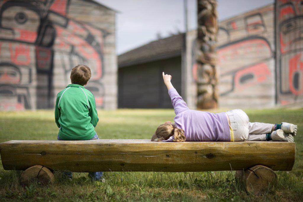 Two children sitting on a wooden bench.