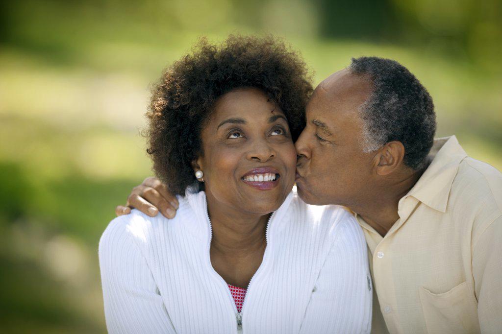 Happy mature man gives his smiling wife a kiss on the cheek.