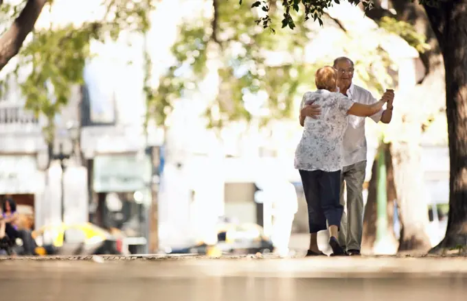Senior couple dancing together in the street.