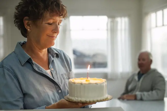 Happy mature woman holding a birthday cake.