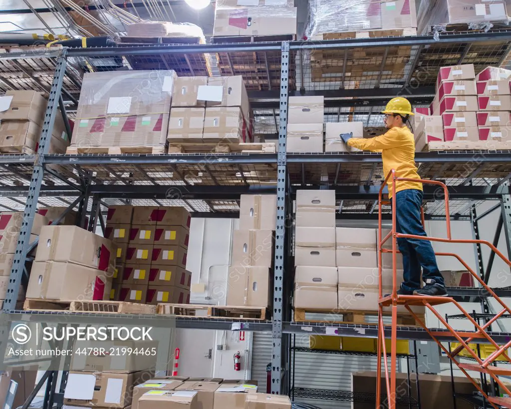 Man Retrieving Box From Large Warehouse 