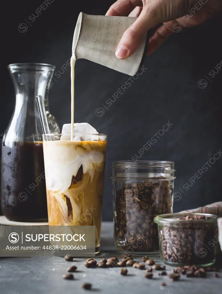 Woman pouring milk in to an iced coffee