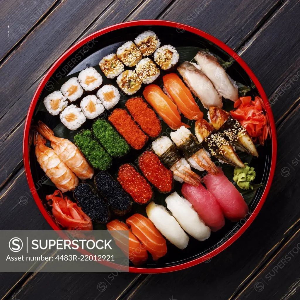 Sushi Set gunkan, nigiri and rolls served in traditional Japan black Sushioke round plate