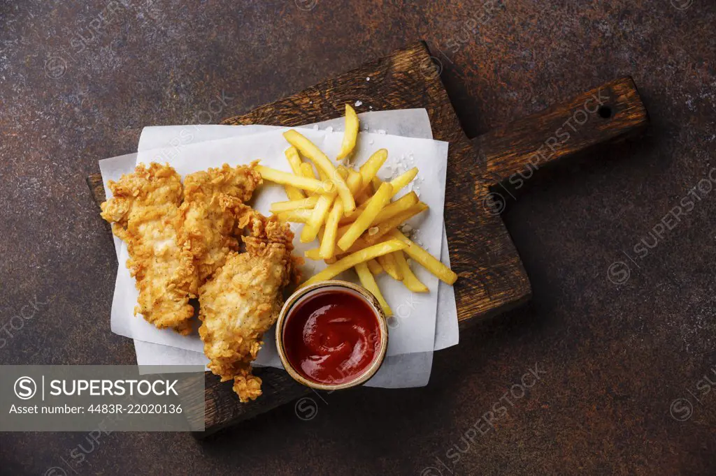 Fish and Chips british fast food with ketchup sauce on dark background