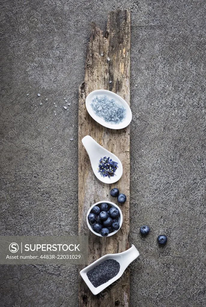Blue food: blue salt, oolong blend tea, blueberries, poppy seeds on grey background