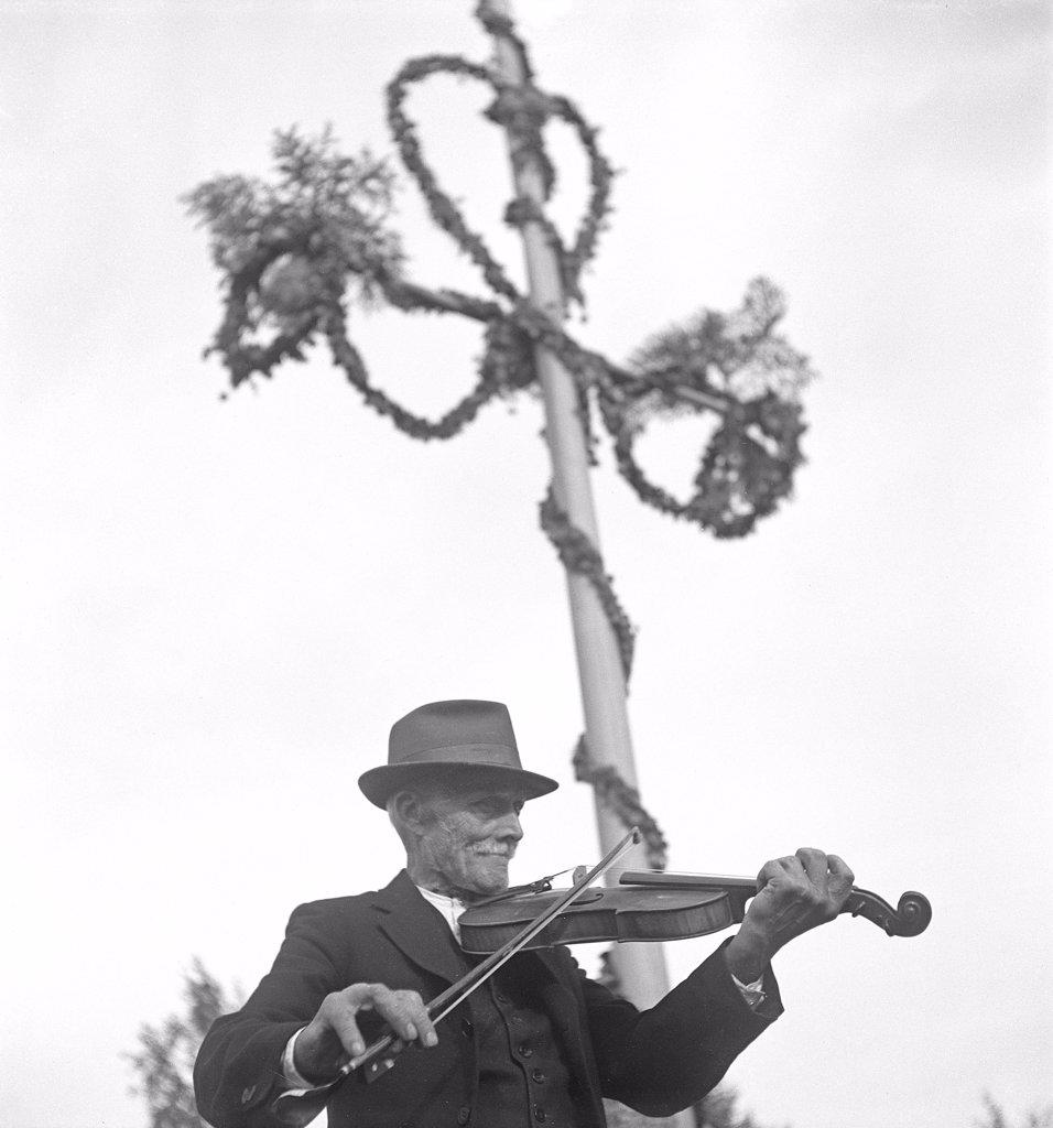 Musician at midsummer. An elderly man is playing the violin at an open air midsummer fiest. Sweden Photo Kristoffersson Ref 219-2. Sweden 1940s