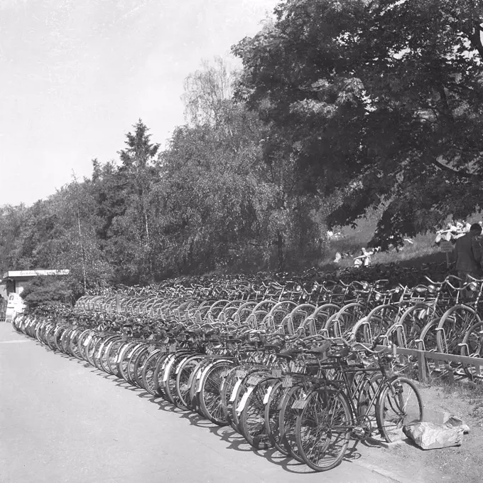 1940s cyclists. Bicycles are parked at a public bath a warm summer day. The bicycles are properly parked in cycle racks. Note the registration signs on the bikes that was a mandatory item at the time. May 1940. Photo Kristoffersson 129-11