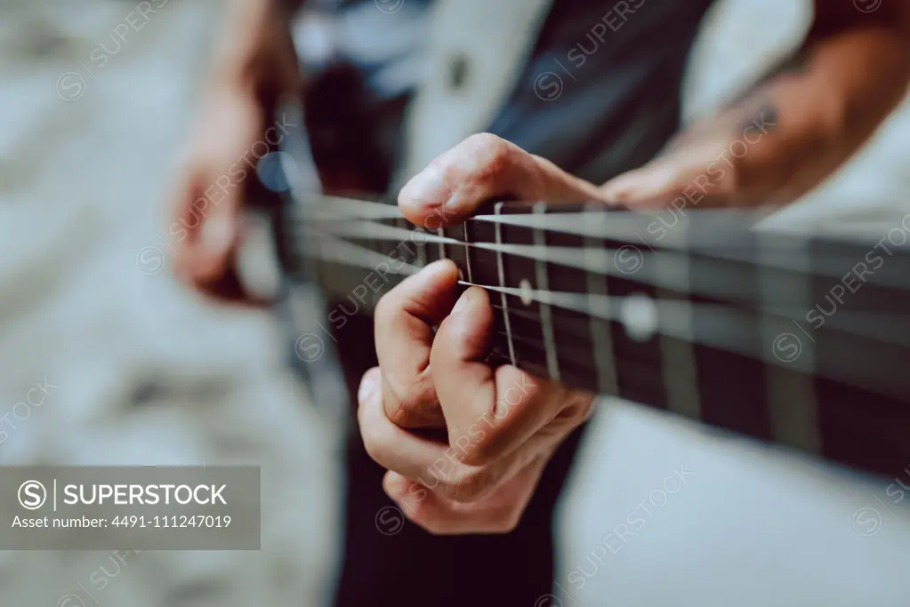Man clamping strings on guitar neck