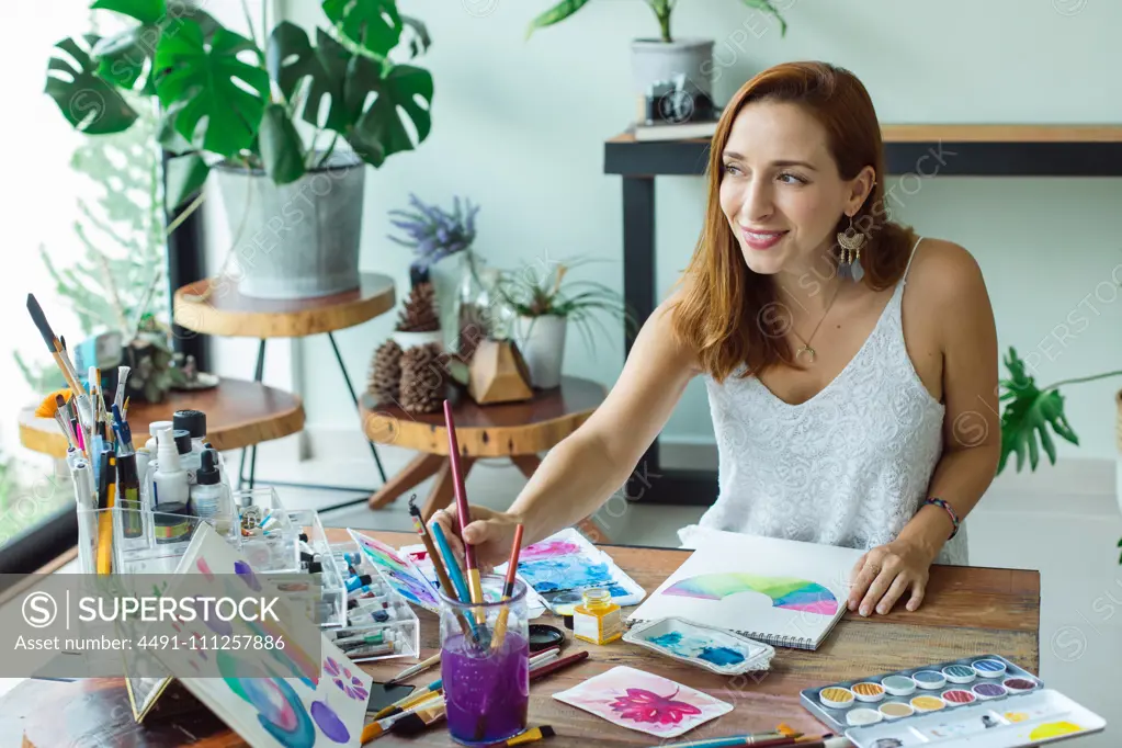 Latin artist painting with watercolor in her studio
