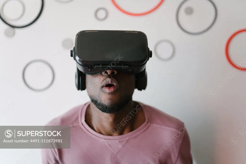 Amused African American man in VR glasses spending time in virtual reality staying at home;Excited black man in VR glasses enjoying time at home
