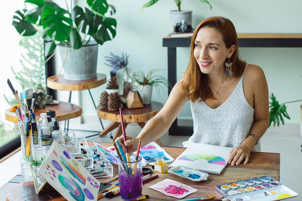 Latin artist painting with watercolor in her studio