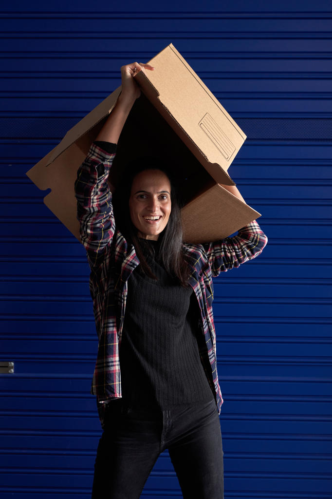 Beautiful woman with box on her head organizing her move in a storage room