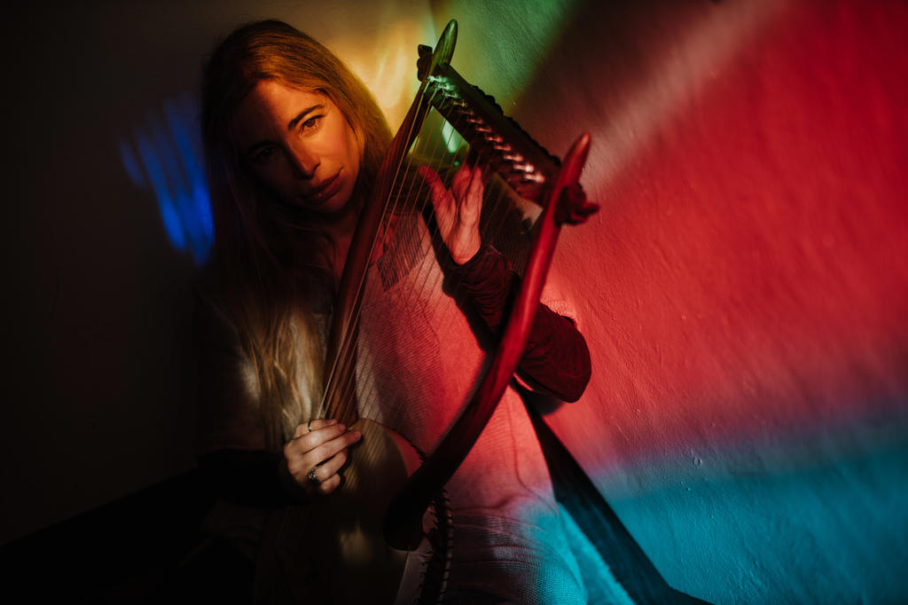Woman playing lyre under colorful light