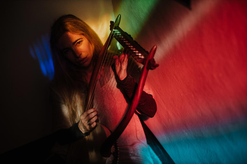 Woman playing lyre under colorful light