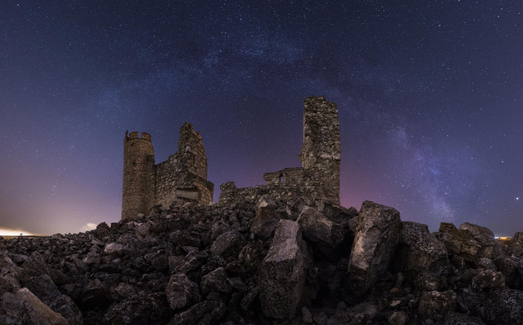 Remains of ancient castle under Milky Way at starry night