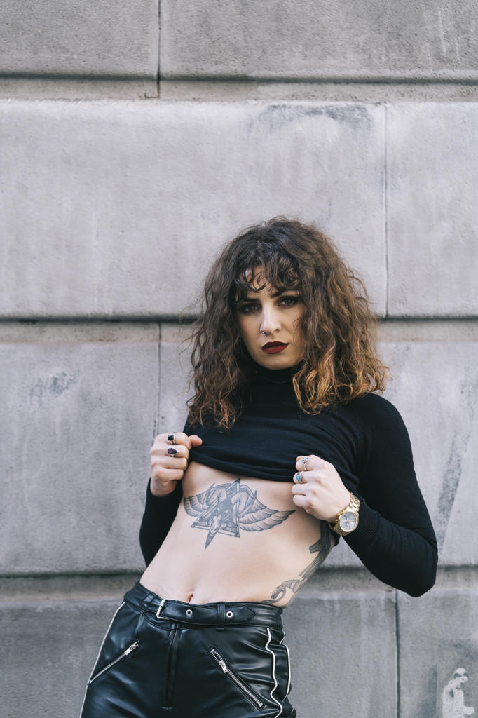 Young tattooed woman posing sensual in the street