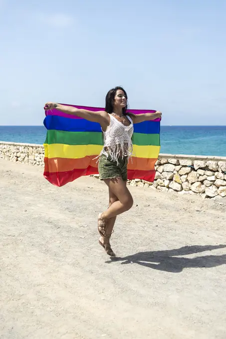 Portrait of a pretty hispanic woman playing with a lgtb flag