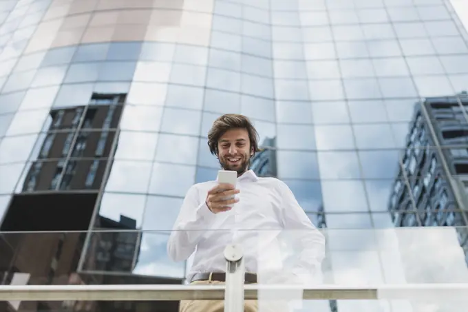 Portrait of confident businessman in white shirt using phone