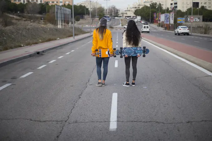 Two girls who play in the street with longboard