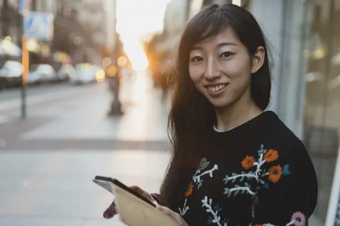 Asian woman browsing smartphone on street