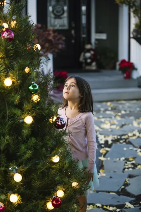 Little Adorable Girl decorating Christmas Tree