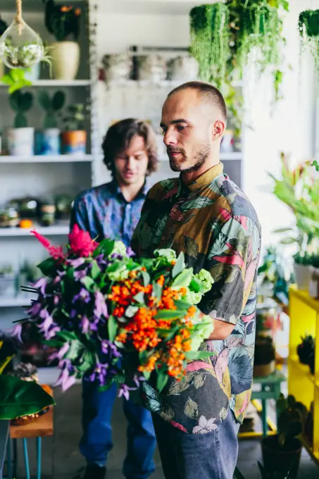 Two men working in the flower shop. Creative occupation, small business. Retailing.