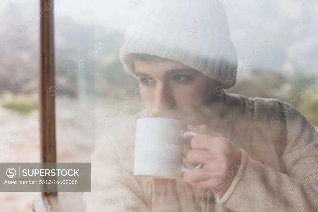 Close up of a young man drinking coffee seen through cabin window