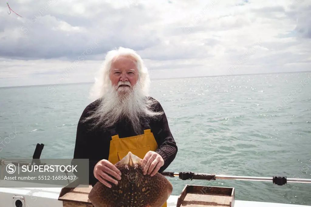 Portrait of fisherman holding ray fish on boat