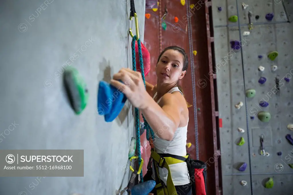 Determined woman practicing rock climbing in fitness studio