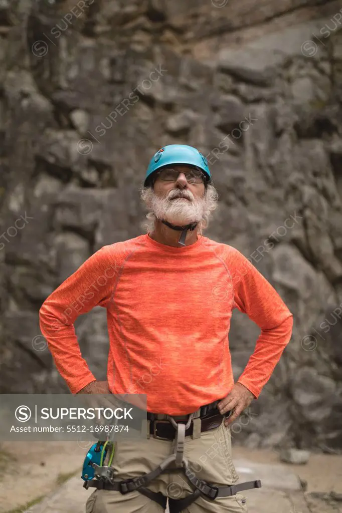 Thoughtful senior man wearing safety equipment during mountaineering