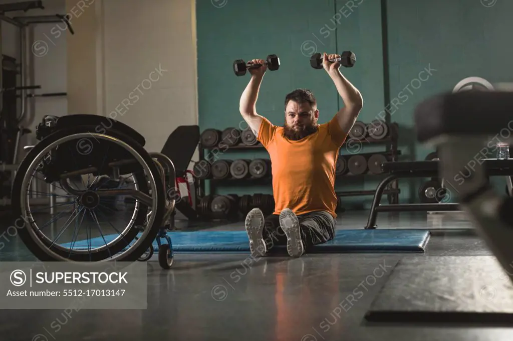 Handicapped man exercising with dumbbell in gym