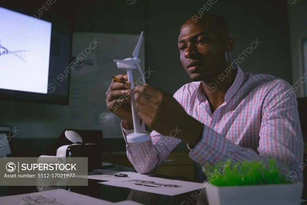 Male executive examining a windmill model in office