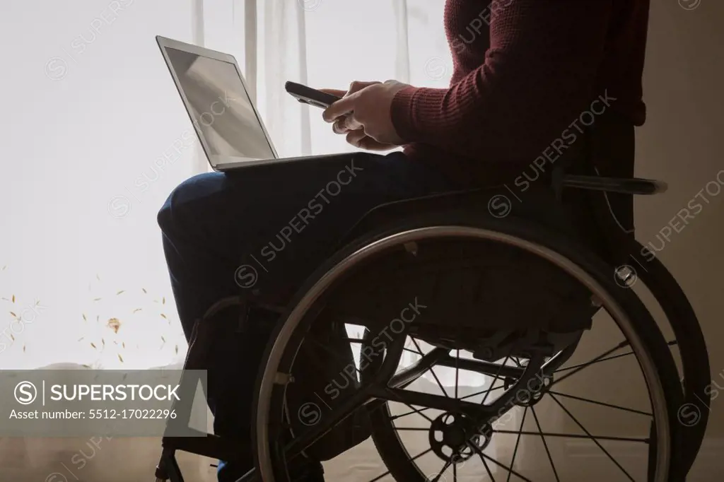 Mid section of disabled man using mobile phone at home