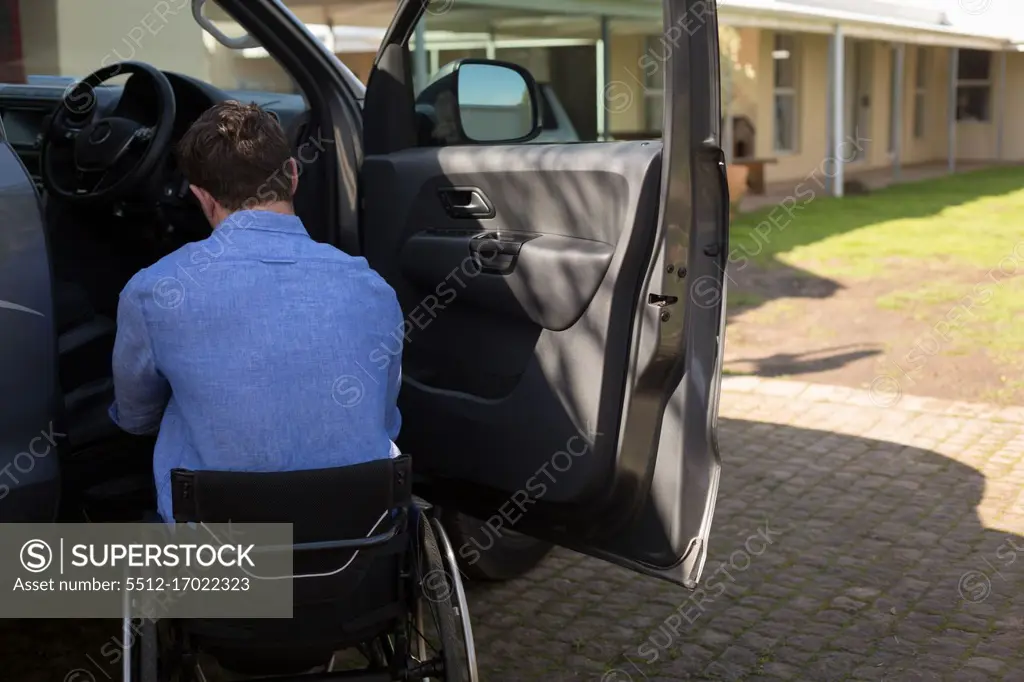 Rear view of disabled man in wheelchair near car 