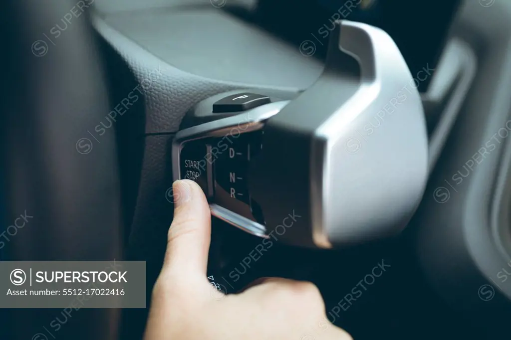 Businesswoman pushing the start stop button in a car