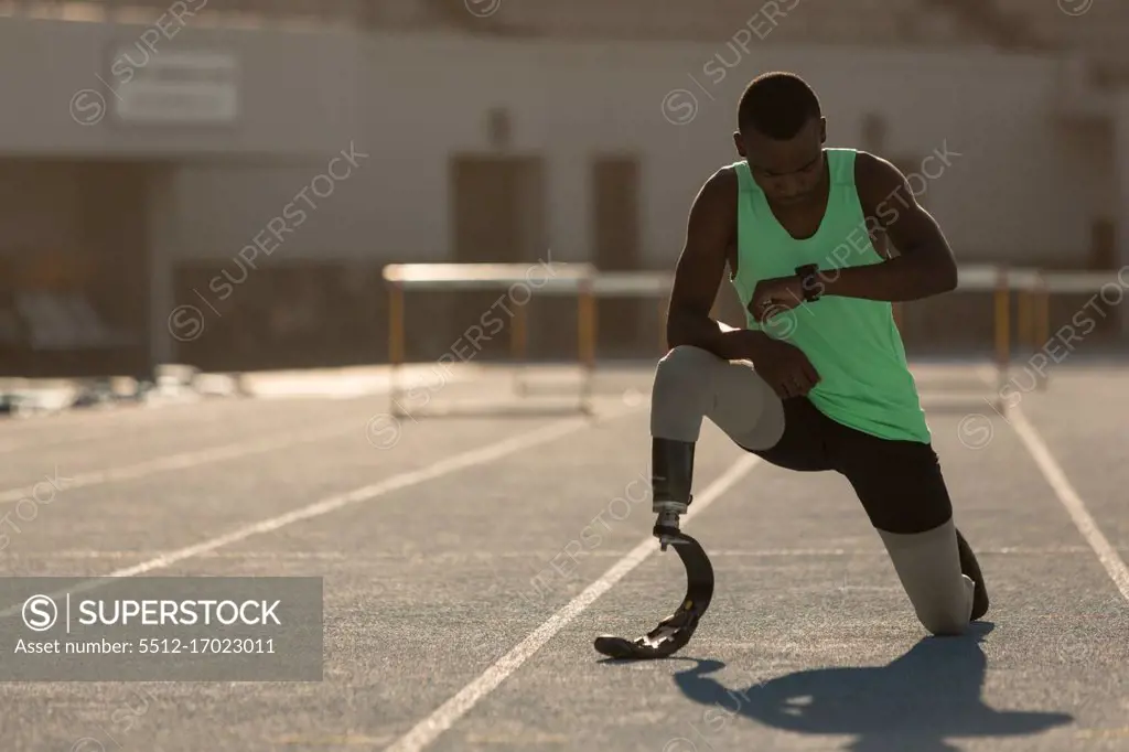 Male disabled athletic checking time on a running track