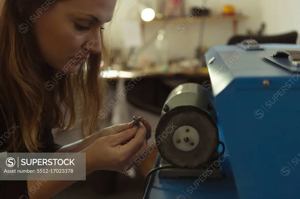 Jewelry designer using sharpening machine in workshop