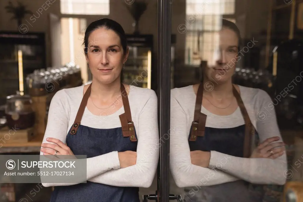 Portrait of female staff standing with arms crossed in supermarket